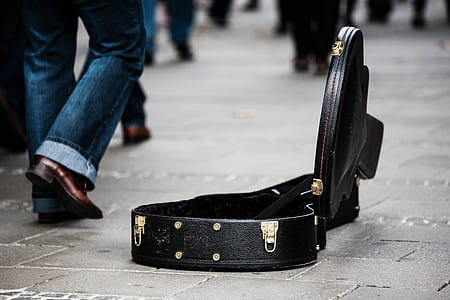 man wearing blue jeans beside the opened black leather guitar case thumbnail