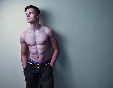 man wearing black bottoms leaning on white wall thumbnail