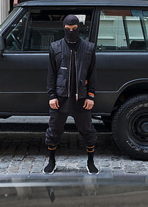 man wearing balaclava standing near car thumbnail