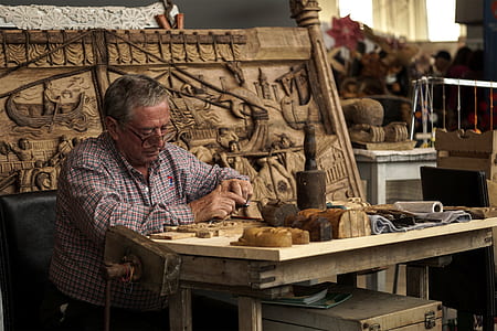 man sitting beside carved panel thumbnail