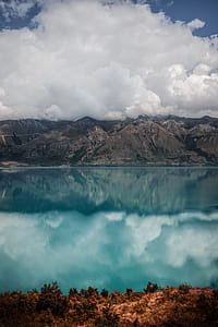 mountains near body of water under white clouds during daytime thumbnail