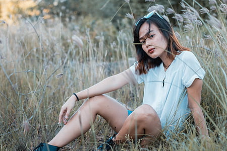 woman wearing white shirt and short shorts sitting at grass thumbnail