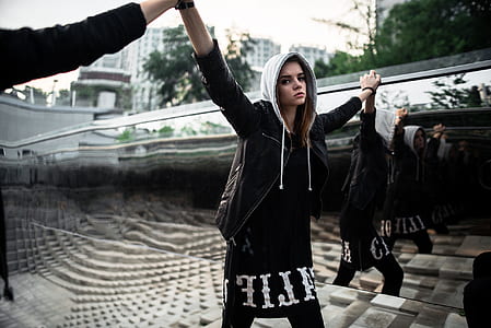 woman wearing black and white pullover hoodie raising her hand thumbnail