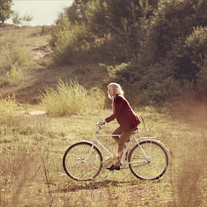 woman riding bike near plant thumbnail