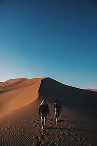 two women walking on a desert during sunset thumbnail