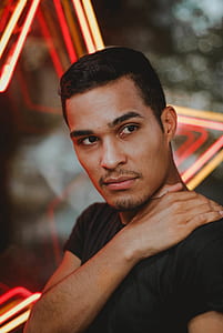 shallow focus photography of man in black crew-neck T-shirt holding his shoulder thumbnail