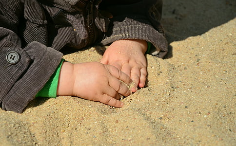closeup photo of kid wearing black corduroy jacket holding brown sand thumbnail