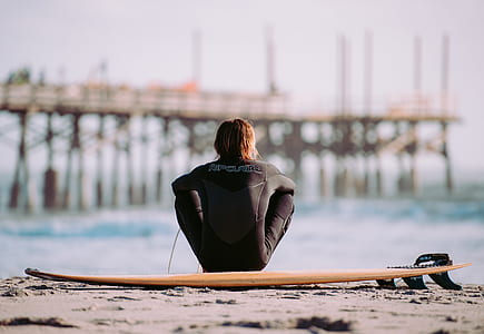 man sitting on seashore near brown dock during daytime thumbnail