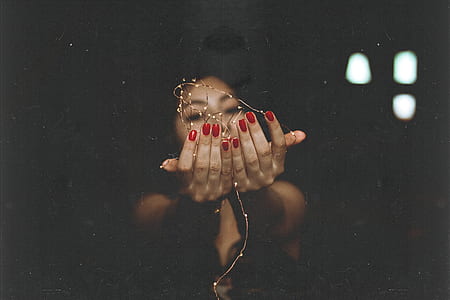 low light photography of woman holding string lights thumbnail