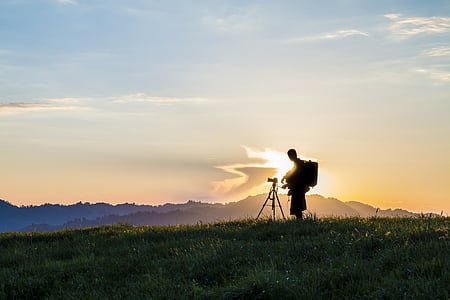 man standing beside tripod thumbnail
