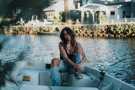 woman wearing black tank top sitting on boat near body of water thumbnail