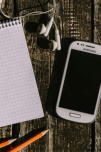 White smartphone with various items on a wooden background thumbnail