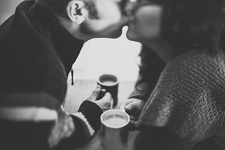 man and woman enjoying coffee while man pecks on woman thumbnail