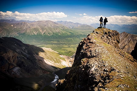 two people standing on mountain peak during daytime thumbnail