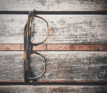 black and brown tortoiseshell eyeglasses on wooden surface thumbnail