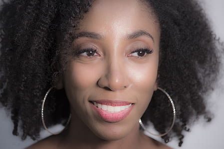 close-up photo of smiling woman wearing pair of silver-colored hoop earrings thumbnail