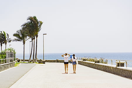 two women walking beside beach walk at daytime thumbnail