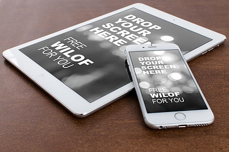 silver iPhones 6 and iPad on top of desk thumbnail
