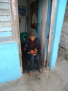 man sitting on chair beside white and blue door thumbnail