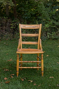 brown wooden chair near trees on green grass field at daytime thumbnail
