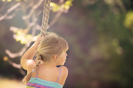 girl playing in swing during daytime thumbnail