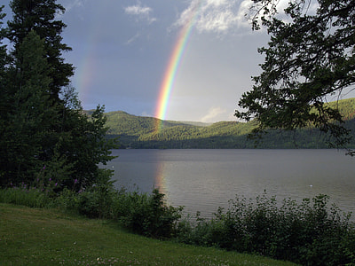 person taking photo of rainbow under blue sky during daytime thumbnail