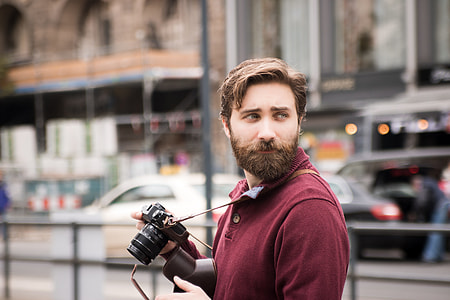 person wearing red collared tops holding black DSLR camera thumbnail