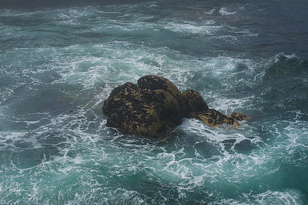 brown rock formation on body of water thumbnail