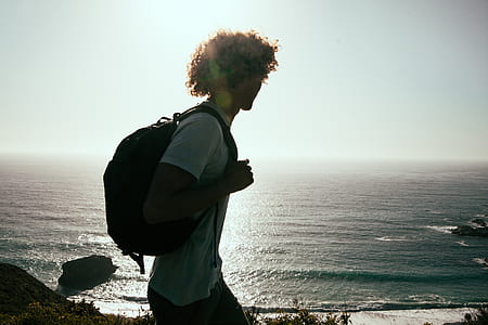 man carrying backpack with sea below thumbnail