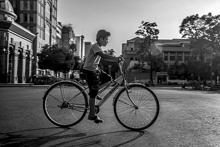 grayscale photography of boy riding step-through bicycle at street thumbnail