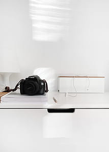 black Canon DSLR camera on white printer paper near wall thumbnail