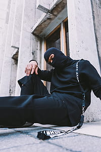 man sitting on concrete floor with black lanyard on his shoulder thumbnail