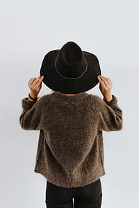 A woman in a brown sweater with a black hat on her head thumbnail