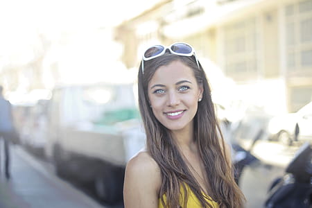 A young blonde woman wearing a yellow dress and sunglasses posing outdoors thumbnail