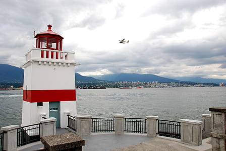 white and red lighthouse under white clouds thumbnail