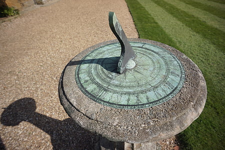 close-up photo of round grey and teal concrete sundial near green lawn thumbnail