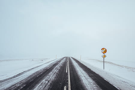 red and brown signage beside road filled with snow thumbnail