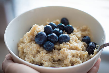 person holding bowl of oats with blue berries thumbnail