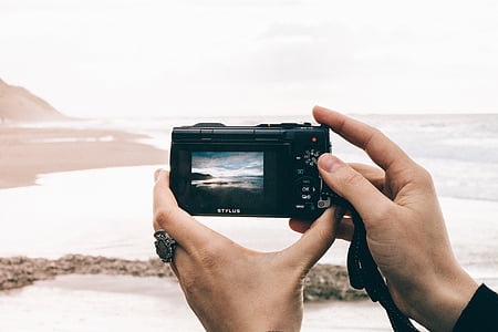 person holding black point-and-shoot camera during daytime thumbnail