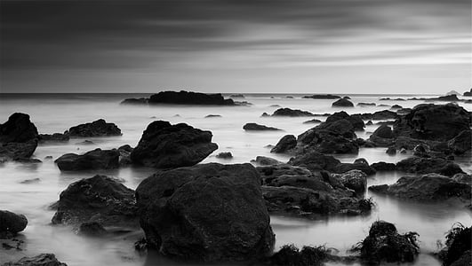 greyscale photo of rocks on body of water thumbnail