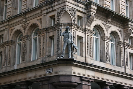 man holding guitar statue during daytime thumbnail