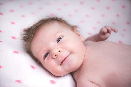 baby lying on white and pink bed thumbnail