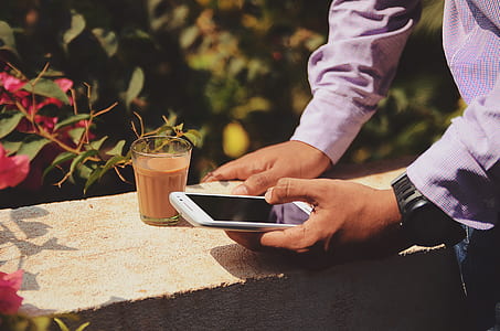 person in purple dress shirt holding smartphone near clear drinking glass thumbnail