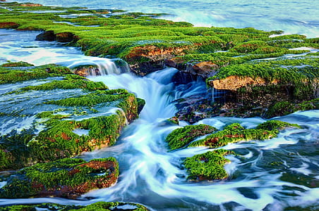 waterfalls and grass covered island during day thumbnail