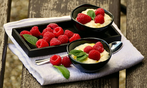 Raspberries on Black Rectangular Tray Beside Black Round Bowl With 3 Raspberries Beside Silver Spoon on Top of White Textile thumbnail