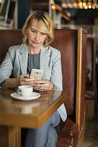 woman holding smartphone while sitting on chair near table thumbnail