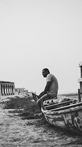 grayscale photography of man sitting on canoe thumbnail