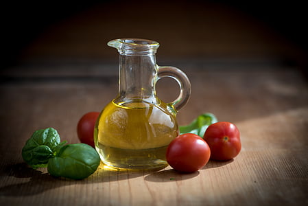 clear glass cruet near cherry tomatoes and green leaves on brown surface thumbnail