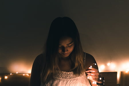 woman wearing white camisole holding string lights thumbnail