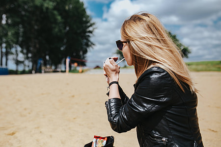 Young woman wearing a leather jacket and sunglasses on the beach thumbnail